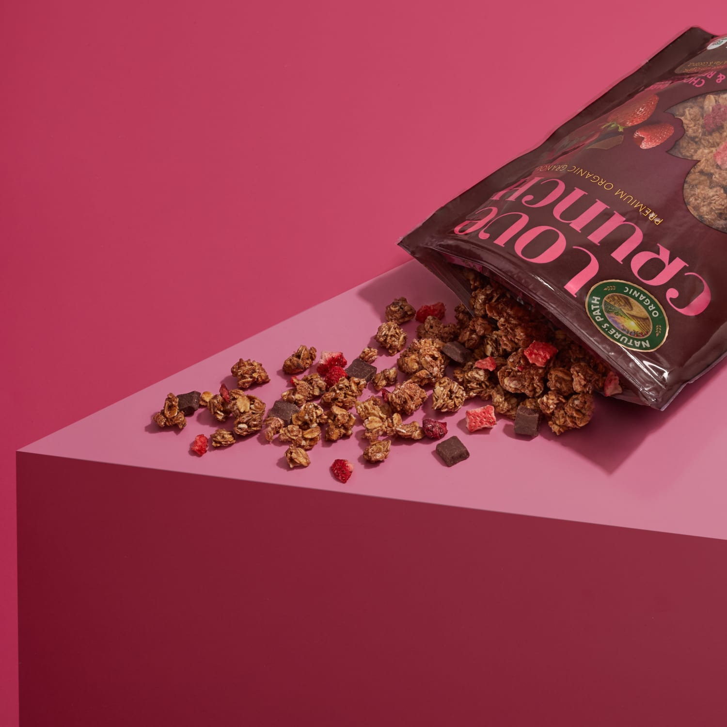 A bag of Nature's Path Love Crunch granola is tipped over, spilling its contents on a table top.