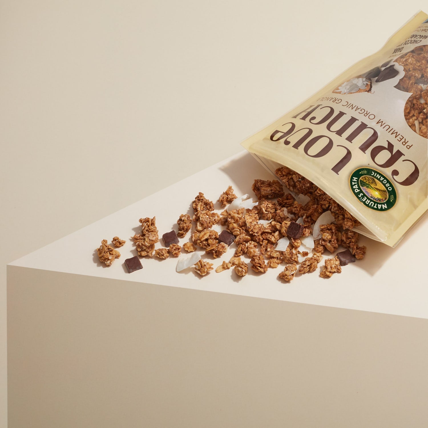 A bag of Nature's Path Love Crunch granola is tipped over, spilling its contents on a table top.